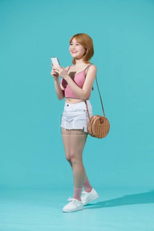 Photo for Full body of a teenager girl texting in a smart phone isolated on a turquise background - Royalty Free Image