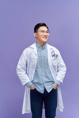 Téléchargez les photos : Heureux jeune asiatique homme médecin en blanc uniforme avec stéthoscope sourire isolé dans studio - en image libre de droit