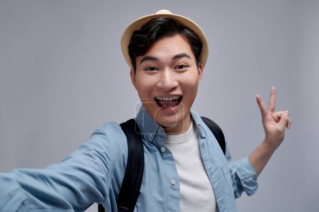 Photo for Beautiful excited young man makes self portrait with v sign smiling - Royalty Free Image
