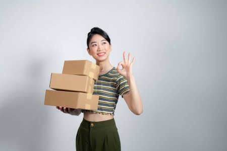 Téléchargez les photos : Femme d'affaires avec porter la livraison et montrant le signe correct, fond blanc - en image libre de droit