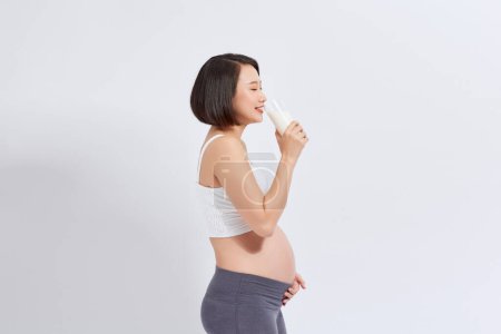 Téléchargez les photos : La fille enceinte boit du lait. isolé sur fond blanc - en image libre de droit