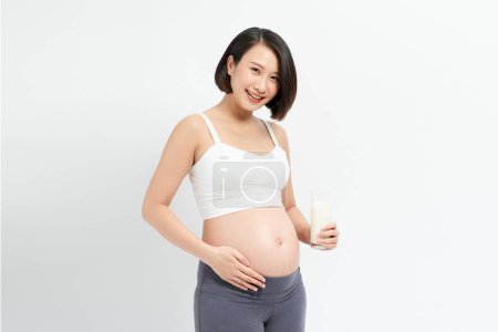 Téléchargez les photos : Femme enceinte buvant du lait sur fond blanc. - en image libre de droit