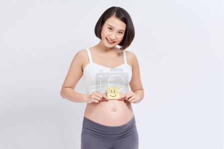 Téléchargez les photos : Ventre enceinte avec autocollant jaune sur fond blanc - en image libre de droit