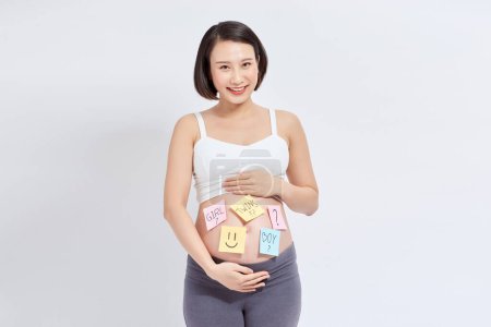Photo for Choosing baby name. Confused pregnant woman with question marks on paper stickers on tummy - Royalty Free Image