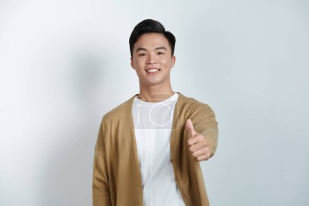 Photo for Attractive cheerful young man standing isolated over white background, showing thumbs up - Royalty Free Image