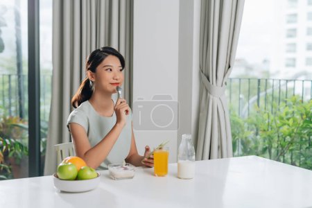 Foto de Mujer feliz usando smartphone con comida en la mesa - Imagen libre de derechos