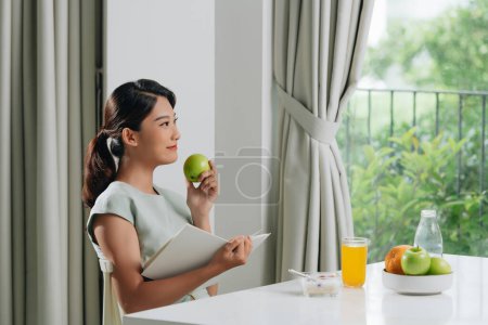Photo for Beautiful young woman reading book during coffee break at home - Royalty Free Image