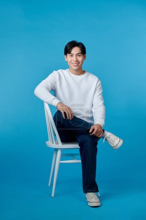 Photo for Asian man sitting on chair isolated on blue background - Royalty Free Image