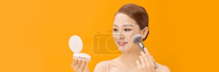 Téléchargez les photos : Attrayant belle asiatique fille obtenir naturel maquillage en utilisant brosse maquillage sur bannière fond - en image libre de droit