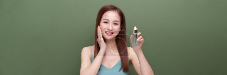 Foto de Hermosa asiático hembra utilizando anti-envejecimiento tratamiento producto en verde, panorama - Imagen libre de derechos