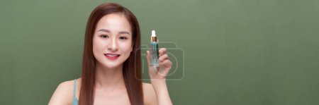 Photo for Young beautiful asian female applying facial serum - Royalty Free Image
