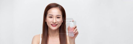 Téléchargez les photos : Souriant jeune femme asiatique montrant des produits de soins de la peau isolés sur fond de bannière. - en image libre de droit