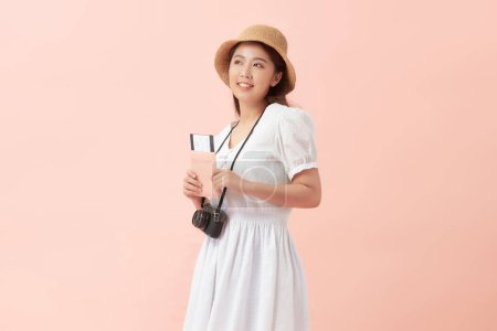 Téléchargez les photos : Happy woman touriste voyage tenant caméra et passeport isolé sur fond rose - en image libre de droit