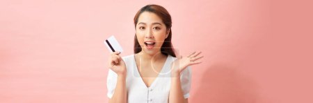 Photo for Excited young asian woman holding credit card in hand, happy about sales and purchases, banner, panorama - Royalty Free Image
