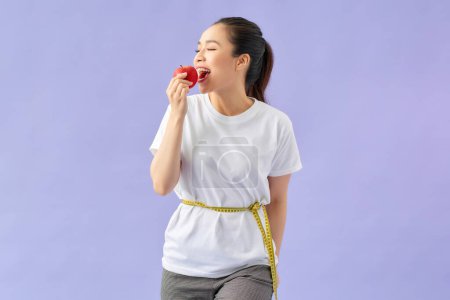 Téléchargez les photos : Femme mesurant sa taille et montrant pomme rouge fraîche à la main. - en image libre de droit