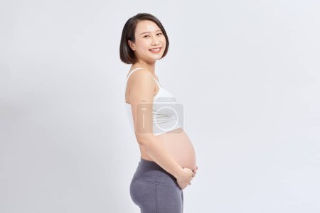 Photo for Pregnant woman caressing her belly over white background - Royalty Free Image