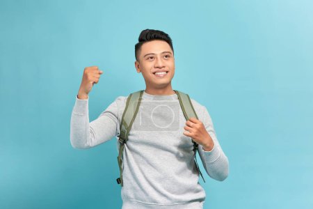 Téléchargez les photos : Portrait de heureux excité jeune touriste asiatique routard homme levant les poings faisant geste de succès - en image libre de droit
