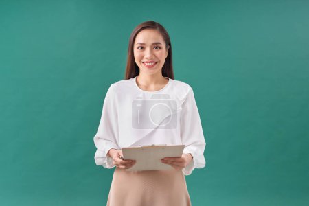 Téléchargez les photos : Belle femme d'affaires prenant des notes sur son presse-papiers isolé sur fond vert - en image libre de droit