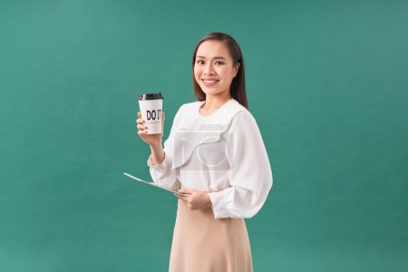 Téléchargez les photos : Jeune femme tenant tablette numérique et tasse en papier isolé sur vert - en image libre de droit