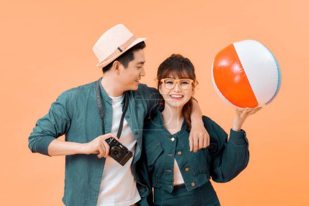 Téléchargez les photos : Jeune couple attrayant avec ballon gonflable et caméra sur fond jaune - en image libre de droit