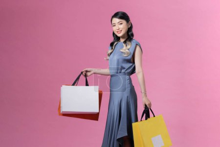 Téléchargez les photos : Asiatique femme tenant des sacs à provisions en plein corps isolé sur fond rose - en image libre de droit