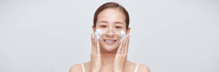 Téléchargez les photos : Bannière de visage de mousse de lavage de jeune femme souriante par gel mousseux naturel - en image libre de droit