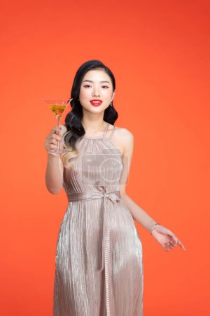 Téléchargez les photos : Jolie jeune femme tenant boisson, vin ou alcool pour une occasion spéciale - en image libre de droit