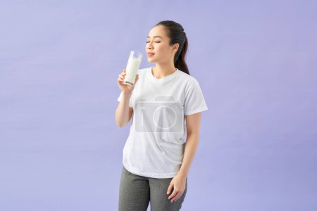 Téléchargez les photos : Agréable belle femme avec un verre de lait dans sa main regardant - en image libre de droit