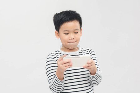 Foto de Pequeño niño emocional jugando con el teléfono inteligente sobre fondo blanco - Imagen libre de derechos