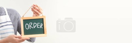 Foto de Mano de empresaria con delantal sosteniendo cartelera, etiqueta o póster para PEDIDO - Imagen libre de derechos