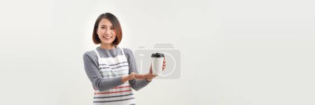 Téléchargez les photos : Jeune femme dans tablier tient deux tasse de papier à emporter isolé sur fond blanc - en image libre de droit