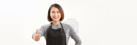 Photo for Cheerful young pretty female cafe staff in black apron show support or like gesture. - Royalty Free Image