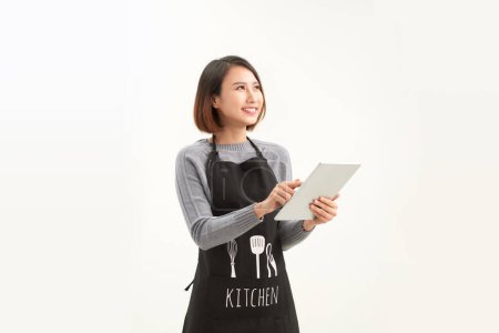 Téléchargez les photos : Portrait de jeune serveuse asiatique café en utilisant une tablette numérique sur fond blanc - en image libre de droit