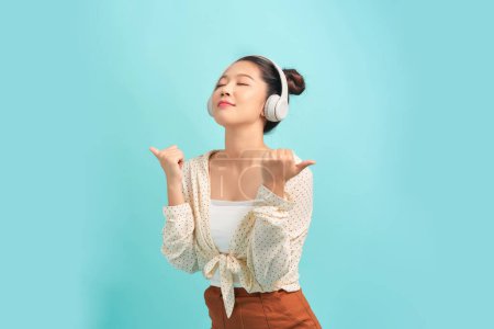 Téléchargez les photos : Heureuse fille excitée portant des écouteurs sans fil, écoutant de la musique, se sentant positive et détendue - en image libre de droit