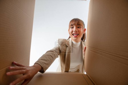 Foto de Dentro de la vista inferior de cartón. asiático chica desembalaje entrega buscando en caja - Imagen libre de derechos