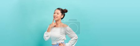 Photo for Beautiful trendy girl touching her lips with finger, looking at camera, isolated on blue background - Royalty Free Image