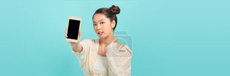 Téléchargez les photos : Jeune femme asiatique en utilisant smartphone sur fond bleu - en image libre de droit