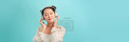 Photo for Happy excited girl wearing wireless headphones, listening to music, feeling positive and relaxed - Royalty Free Image