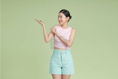 Photo for Attractive pretty girl holding on palm copy empty blank space place isolated on pastel green background - Royalty Free Image