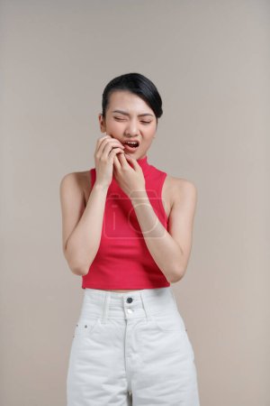 Téléchargez les photos : Belle femme asiatique a un mal de dents isolé sur fond beige. - en image libre de droit