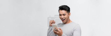 Photo for Happy winner! Young handsome man smiling holding tablet and playing games - Royalty Free Image