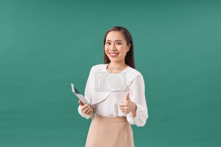 Téléchargez les photos : Attrayant femme d'affaires en vêtements formels tient un appareil tablette et souriant vers la caméra - en image libre de droit