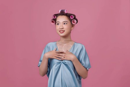 Photo for Beautiful young woman in casual dress and hair curlers on pink background - Royalty Free Image