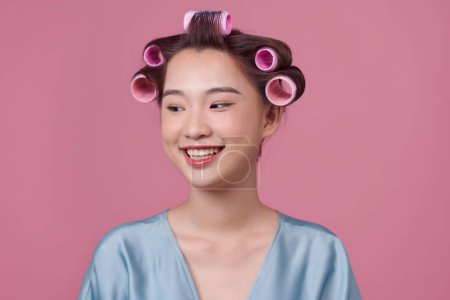 Photo for Beautiful girl in hair curlers on pink background. - Royalty Free Image