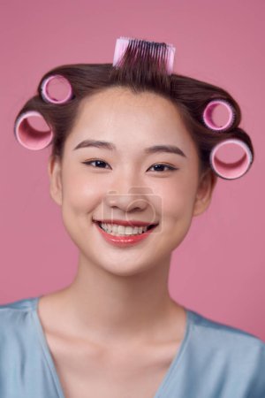 Photo for Beautiful young woman in hair rollers on pink background - Royalty Free Image