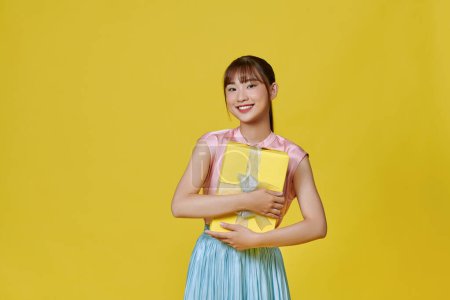 Téléchargez les photos : Portrait pleine longueur d'une femme heureuse tenant cadeau isolé sur un fond jaune - en image libre de droit