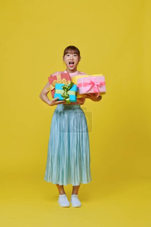 Photo for Isolated portrait of asian smiling woman holding heap of gift boxes. - Royalty Free Image