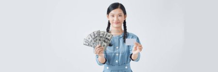 Foto de Mujer feliz sosteniendo dinero y tarjeta de crédito con cara reflexiva - Imagen libre de derechos