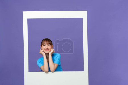 Téléchargez les photos : Jeune dame habillée vêtements bleus souriant regardant par la fenêtre blanche - en image libre de droit