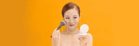 Téléchargez les photos : Attrayant belle fille obtenir maquillage naturel en utilisant le maquillage au pinceau sur fond de bannière - en image libre de droit